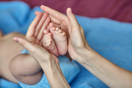 Mother's hands carefully holding baby's feet with love, selective focus, closeupの写真素材