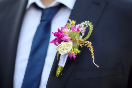 Colorful wedding boutonniere on suit of groom, closeup