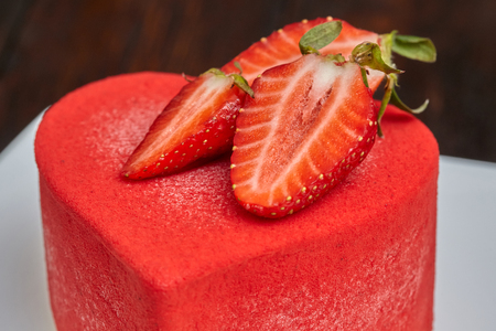Red strawberry cake in the shape of heart on Valentine's Day on wooden backgroundの写真素材