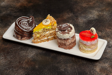Arrangement of cake and candies on long white plate, brown backgroundの写真素材