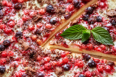 Piece of sweet pizza with currant, redcurrant, mint and chocolate, closeupの写真素材