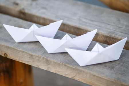 Three white paper boats on wooden bench, closeupの写真素材