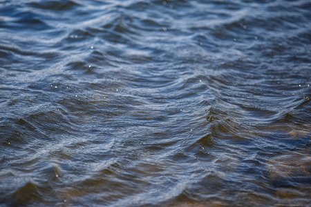 Blue water surface with ripples and reflections texture background