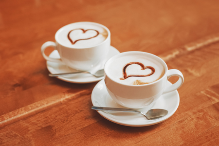 Latte art coffee cups with hearts on table in cafe, vintage toned. Love conceptの写真素材