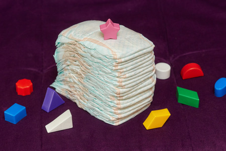 Stack of diapers or nappies with colorful toys on purple background, closeupの写真素材