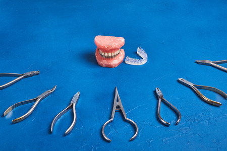 Orthodontic model and set of medical metal orthodontic tools on blue background