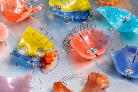 Three colorful dental braces or retainers for teeth on metall background, closeup