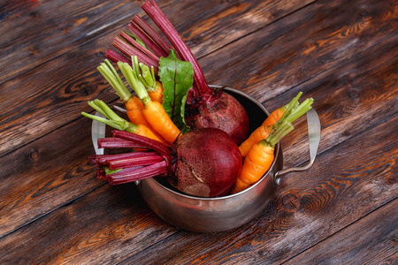 Fresh ripe vegetables bunch on rustic wooden background in metal pot, closeupの写真素材
