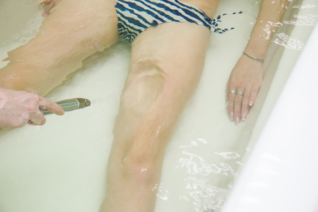 Specialist applynig hydrotherapy in bath. Underwater hydromassage in beauty spa salon