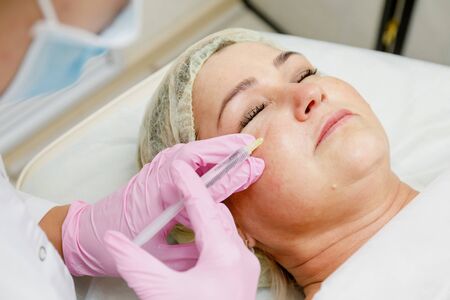 Beautician doing facial injection for woman. Anti-aging revitalization cosmetology procedure