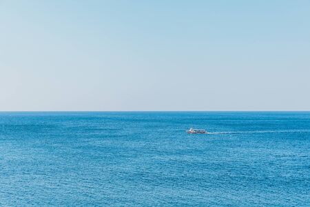 Boat with tourists on blue sea surface aerial view. Nature background