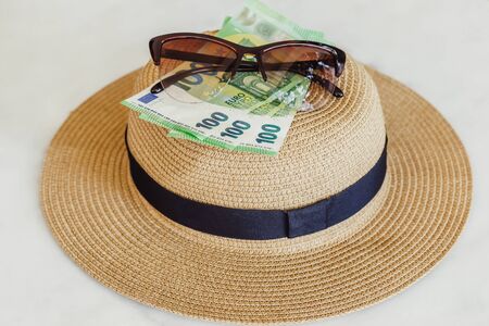 Sun hat with sunglasses and 100 hundredth euro banknotes. Money or vacation concept