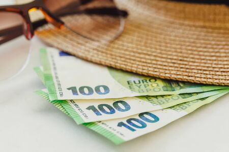 Sun hat with sunglasses and 100 hundredth euro banknotes. Money or vacation concept