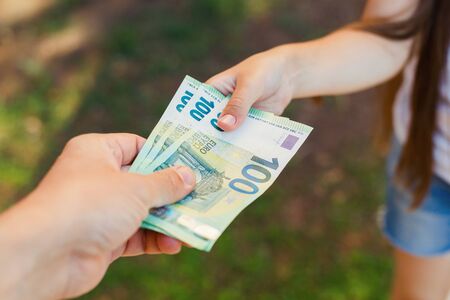 Male hand gives money to a child closeup, hundredth euro banknotesの写真素材