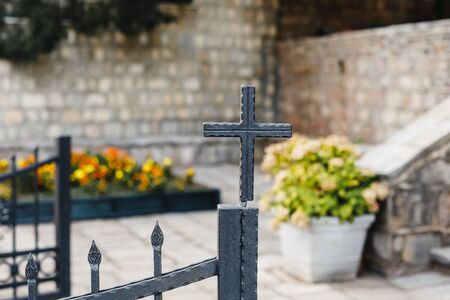 Church yard with flowers and cross on iron fenceの写真素材
