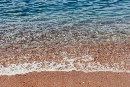 Turquoise sea waves splashing on pebble shore backgroundの写真素材