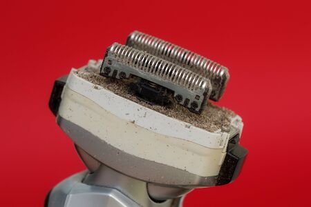 Closeup of dirty razors of foil electric shaver on red backgroundの写真素材
