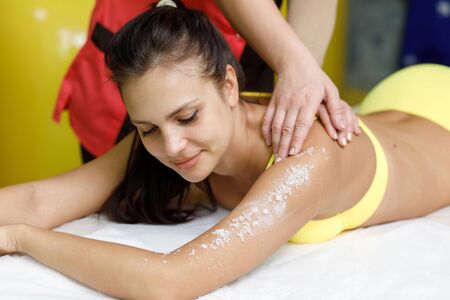 Woman brunette getting salt scrub treatment in beauty or spa salonの写真素材