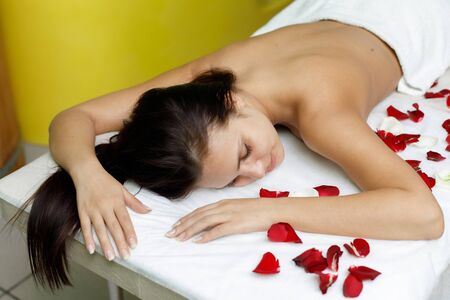 Woman resting in beauty salon with rose petals. Massage in spa salonの写真素材