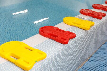 Many yellow and red kickboards in the children's swimming pool