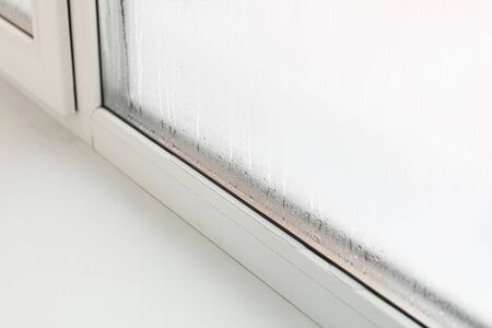Plastic window with damp and water condensation on glass. Bad ventilation in house during cold weatherの写真素材