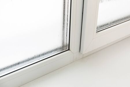 Plastic window with damp and water condensation on glass. Bad ventilation in house during cold weatherの写真素材