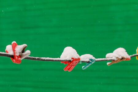 Colorful clothespins on clothesline covered with snow outdoors. Winter scene, housework conceptの写真素材