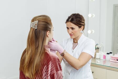 Cosmetologist preparing for permanent makeup, tattooing of lips in beauty salonの写真素材