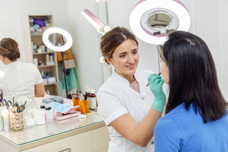 Cosmetologist preparing for permanent makeup, tattooing of lips in beauty salonの写真素材
