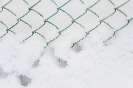 Snow bank and metalic fence, abstract winter backgroundの写真素材