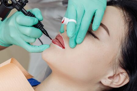 Woman having permanent makeup on lips in beauty salon.の写真素材