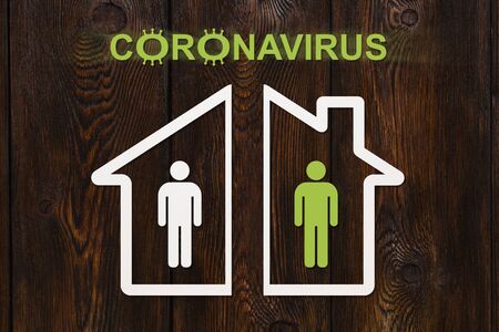 Coronavirus or covid19. Isolation in houses concept. Paper white and green men on wooden backgroundの写真素材