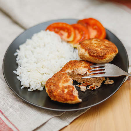 Plate with homemade salmon fish cutlets with rice on wooden table. Healthy food