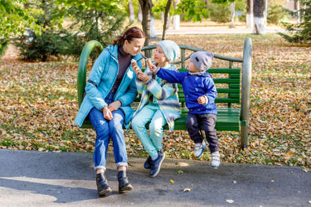 Mother and her children girl and boy eating ice cream and having fun in autumn parkの写真素材