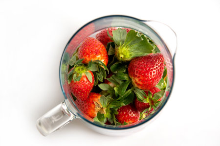 Strawberries with green leaves in a glass jug on a white background. Top View from above.の写真素材