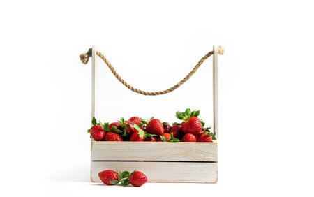Fresh strawberries in a wooden box on a white background. Presentation of berries, seasonal decor.の写真素材