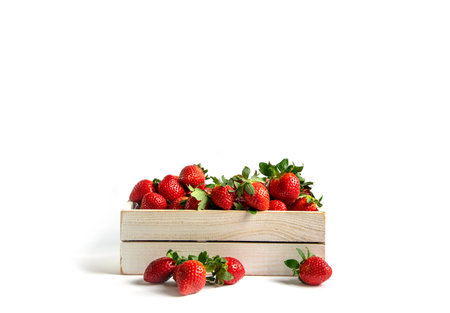 Strawberries in wooden box on a white background with space for text. Presentation of berries, seasonal decorの写真素材