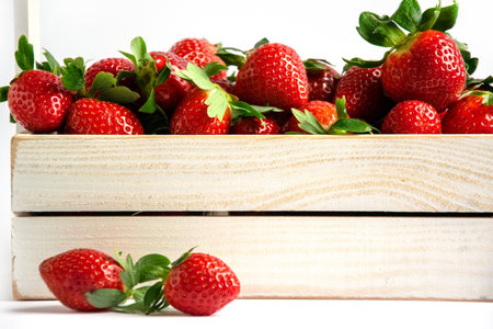 Fresh strawberries close-up in a wooden box on a white background. Impressive background for banner, invitation, business card.の写真素材