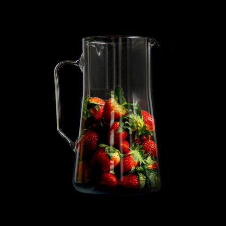 Strawberries in a glass jar with highlights on a black background. Modern strawberry design. Trendy harvest presentation.の写真素材