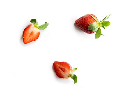 Strawberries on a white background. One whole berry and two halves of juicy fruit. Composition in the style of flat lay.の写真素材