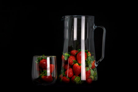Strawberries in a glass dish with highlights on a black background. Fashionable presentation of the harvest.の写真素材