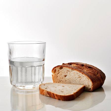 Bread and water close up. Sliced bread and a glass of water on a white background. Minimalism. Studio.の素材
