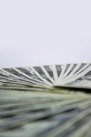 A close-up shot of several US dollar bills arranged in a fan shape, with a white background.の写真素材