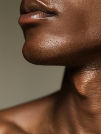 A close-up view of a man's profile showcases his smooth skin and jawline against a soft, neutral background, emphasizing natural beauty and detail.の素材