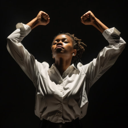 A determined individual stands tall with fists raised in a powerful pose, embodying strength and resilience against a dark backdrop, showcasing a moment of self-empowerment.の素材