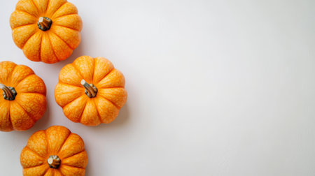 Four vibrant pumpkins sit against a minimalist white background, ideal for fall themes.