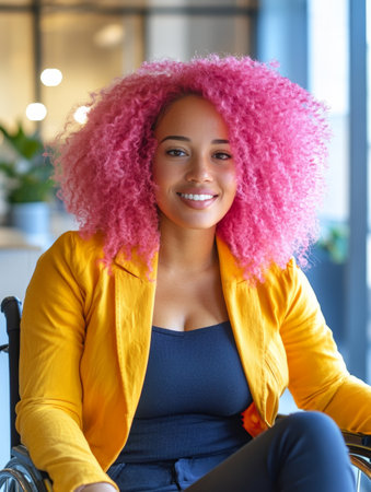 A disabled black woman with pink hair smiles cheerfully in a bright office space, showing diversity and inclusiveness in the workplace.の素材