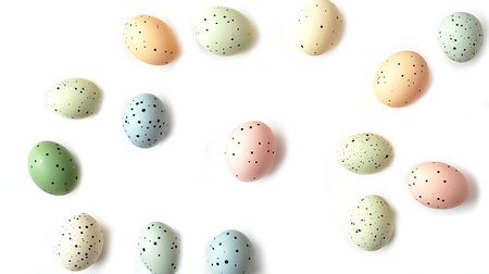Delightful Easter flat lay featuring pastel hand-painted eggs, small bunnies, and fresh green leaves, perfect for spring celebrations.の素材
