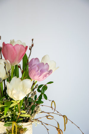 A vibrant arrangement of pink, purple, and white tulips stands in a stylish vase, capturing the essence of spring with fresh foliage.の写真素材