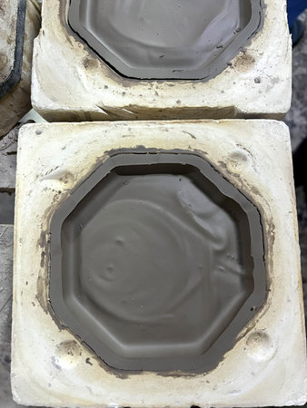 Clay is poured into molds in a pottery workshop, showing the process of ceramic production in...